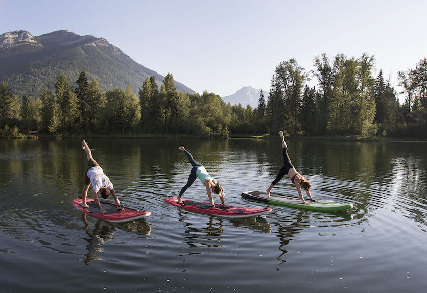 3 Personen machen Yoga auf ihren SUPs auf einem See